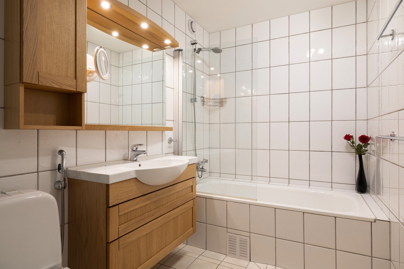 Rommet er innredet med badekar, gulvmontert toalett og baderomsinnredning med nedsunket servant og speil. Galleribilde