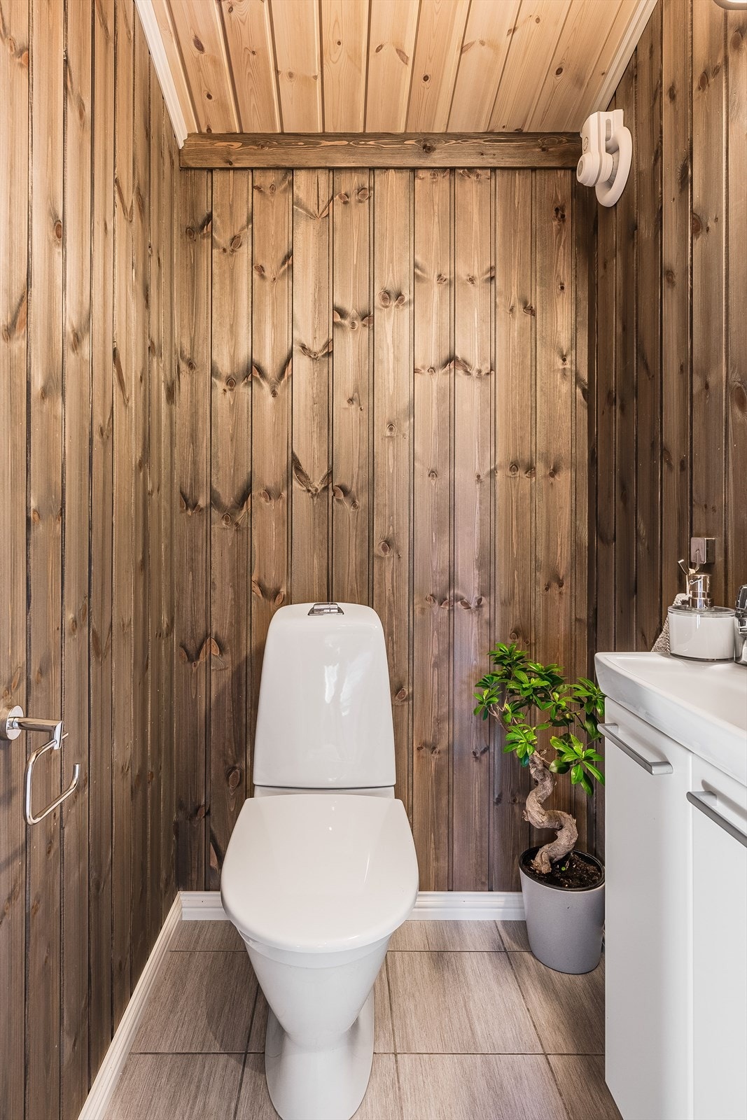 Fint ekstra toalettrom med flislagt gulv og mekanisk avtrekksvifte. Vegg-i-vegg med toalettrommet er det også et praktisk vaskerom. Galleribilde