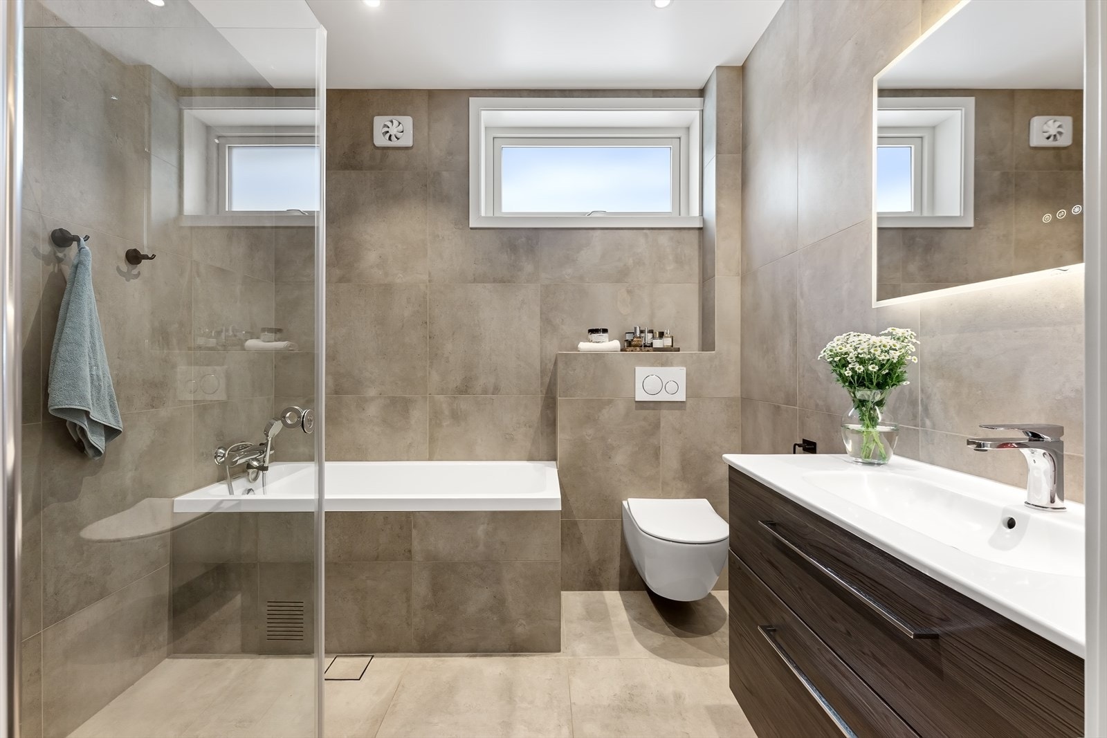 Badet er utstyrt med innredning med nedfelt servant, speil med belysning, innmurt badekar og dusjhjørne med svingbare glassdører. Galleribilde