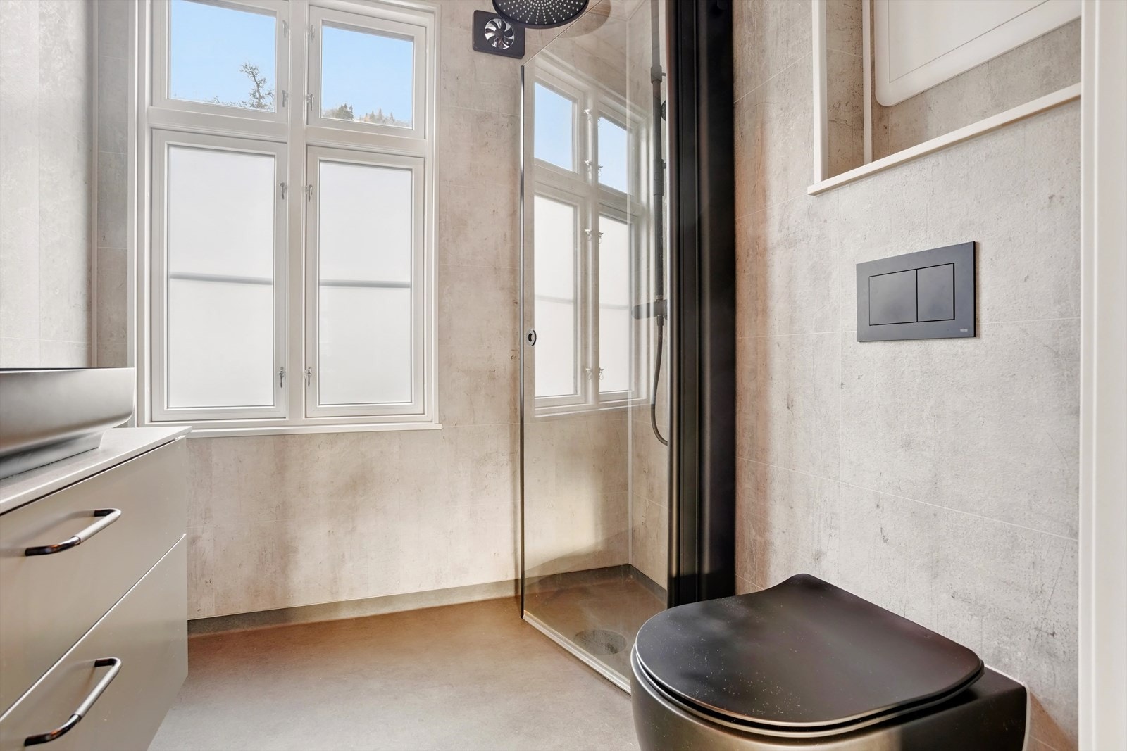 Badet ble totalrenovert i 2024 og er stilrent innredet med sorte detaljer på dusjarmatur og dører, vegghengt toalett og servant Galleribilde