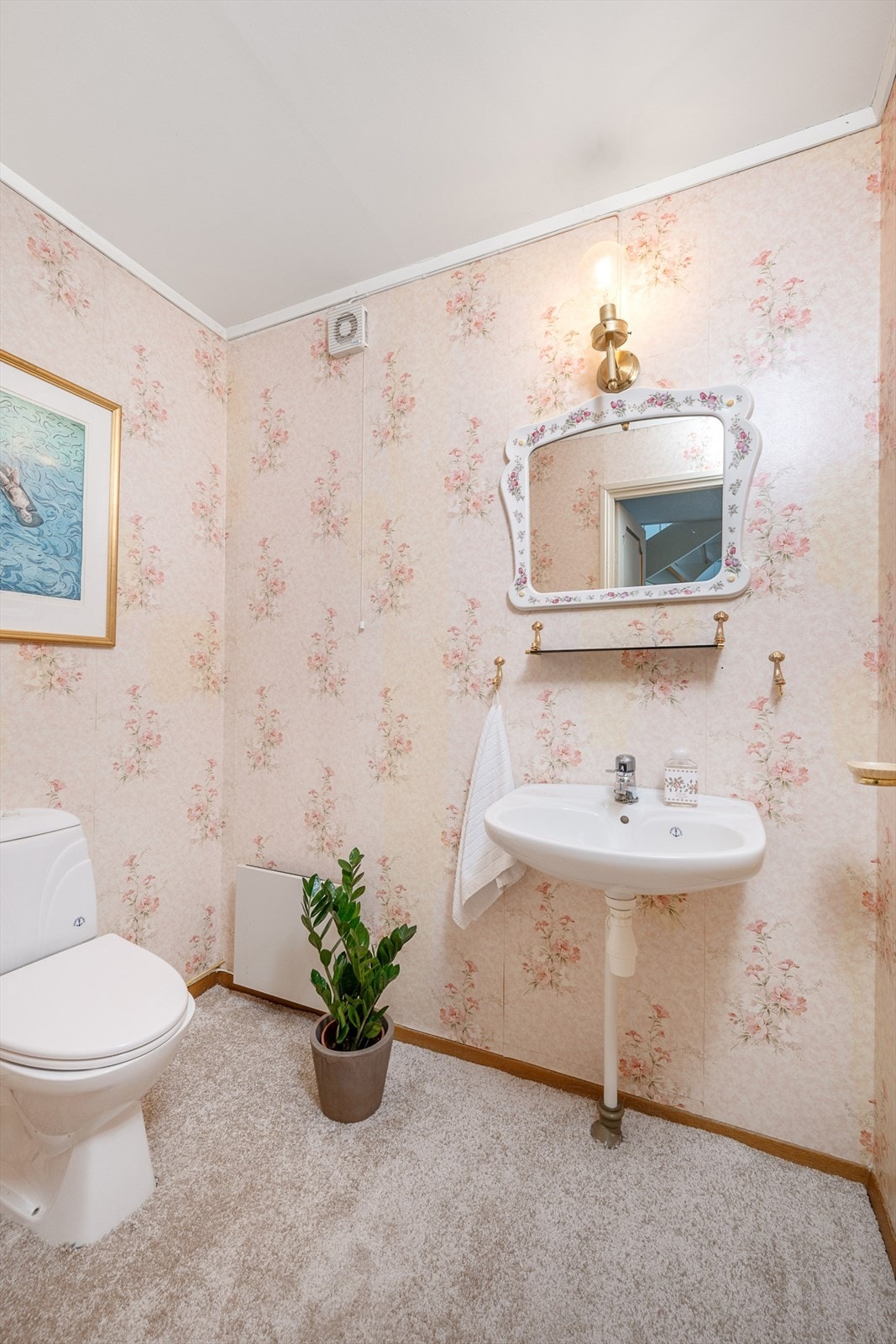 Separat toalettrom i underetasjen med teppe på gulv tapet på veggene. Rommet er innredet med vask og gulvmontert toalett. Galleribilde