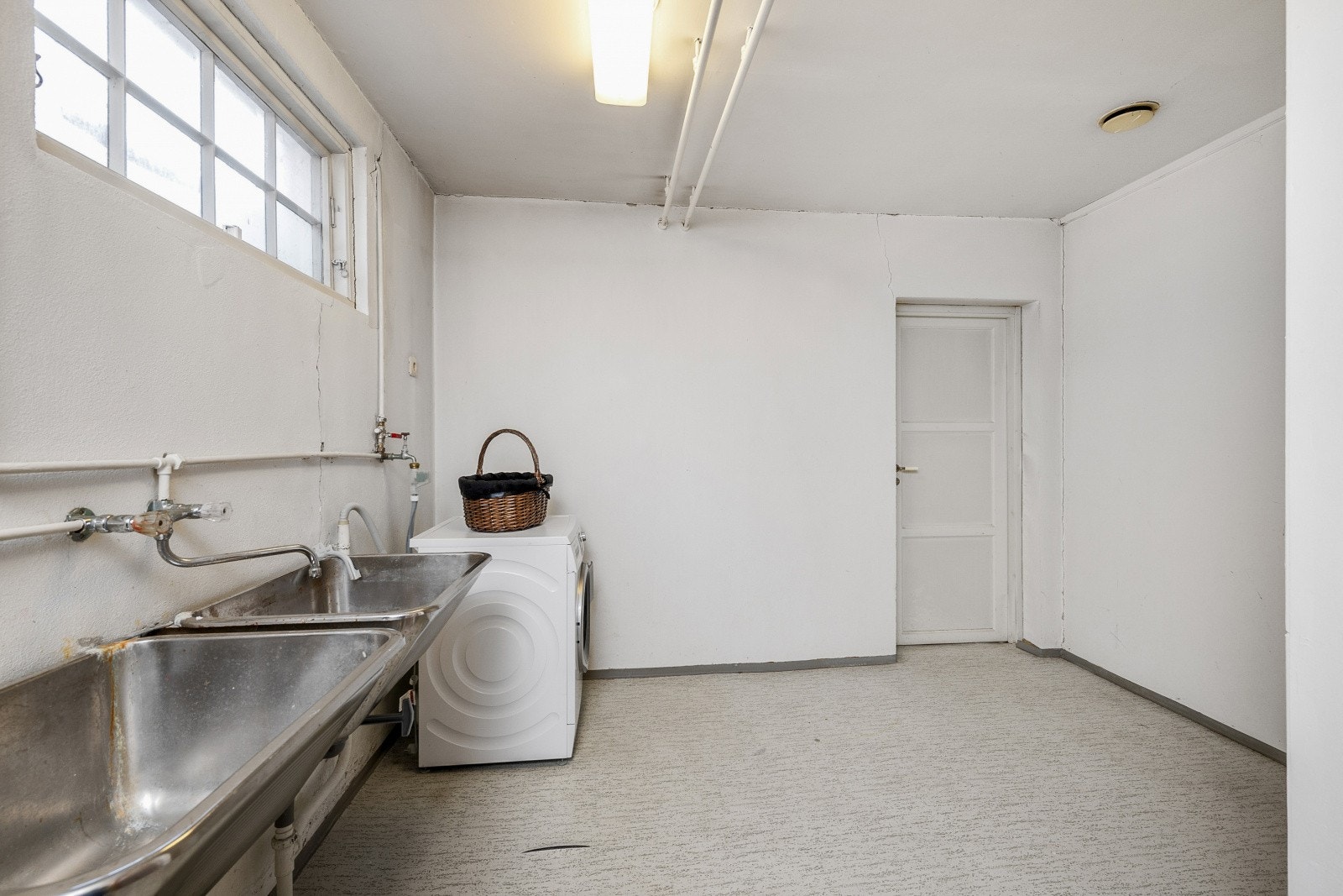Enkelt vaskerom i underetasjen med utslagsvask og opplegg for vaskemaskin. Galleribilde