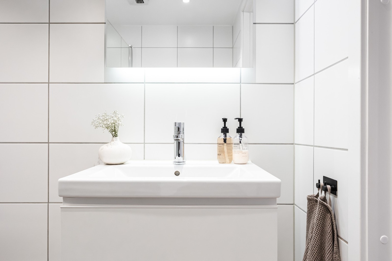 Innredningen består av servantinnredning, speil og lys på vegg over servant, vegghengt toalett og dusjhjørne med svingbare glassdører. Galleribilde