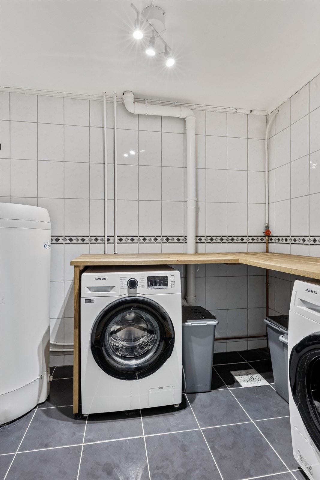 Praktisk vaskerom med flislagt gulv, varmekabler og opplegg for vaskemaskin. Galleribilde