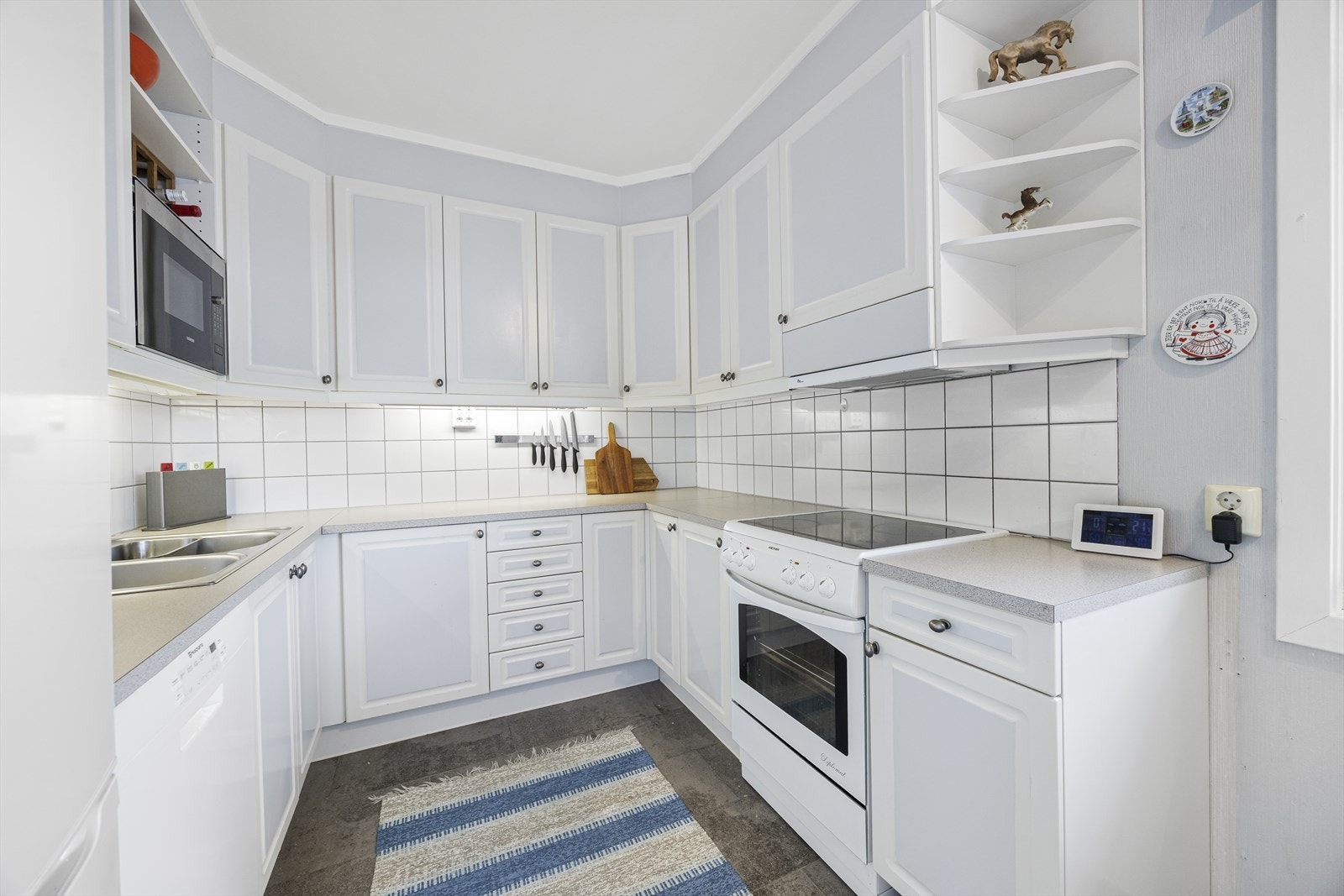 Kjøkkenet er lyst og fint med innholdsrik innredning og fronter i hvit profilert utførelse. Galleribilde