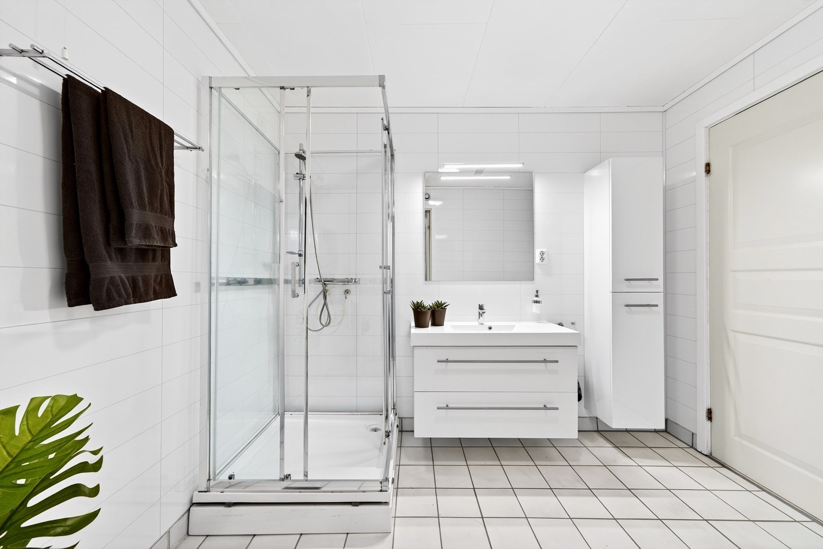 Bad med fliser på gulv og baderomsplater på vegg. Lys baderomsinnredning Galleribilde