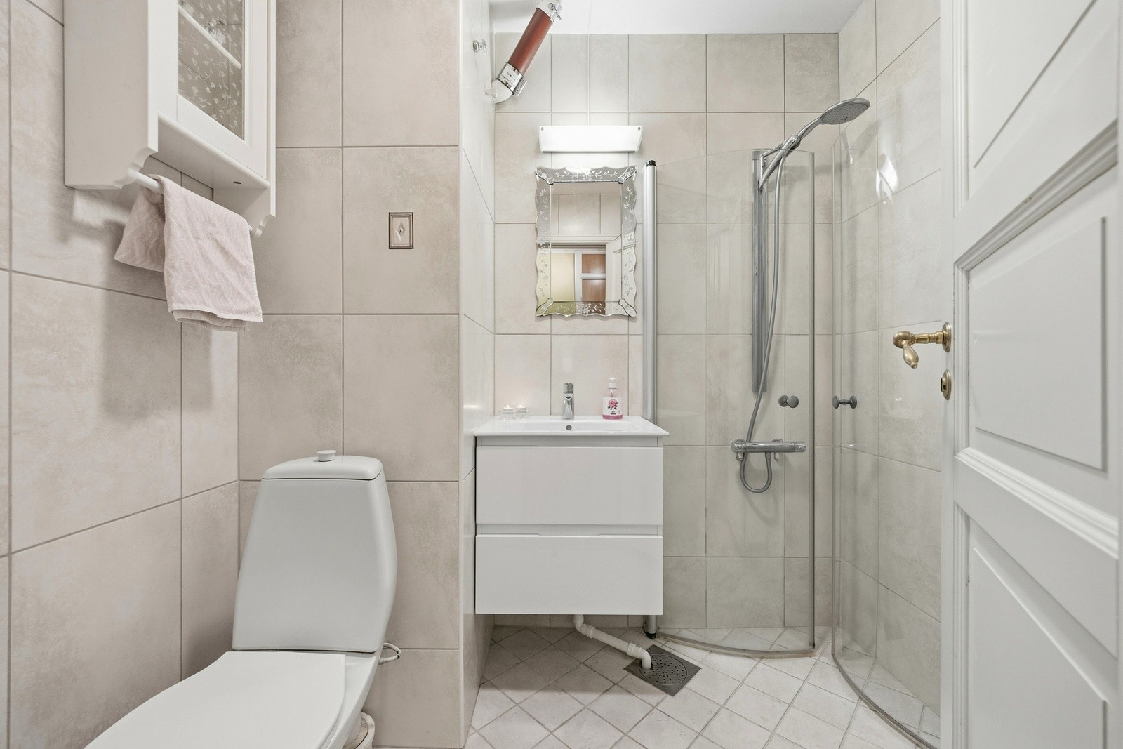 Badet i leiligheten har flislagt gulv og vegghengt servant. Galleribilde