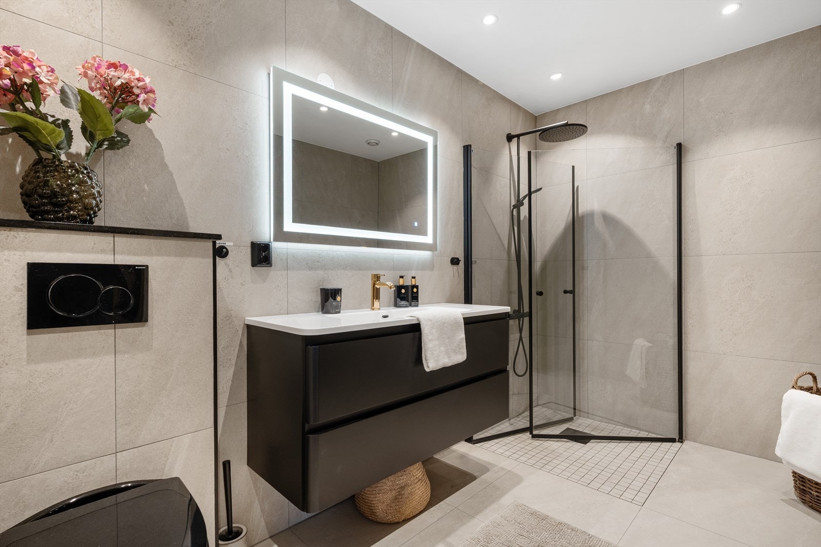 Badet er lekkert utført med bl.a. integrert belysning i speilet, sorte detaljer, storformatfliser og regndusj. Galleribilde