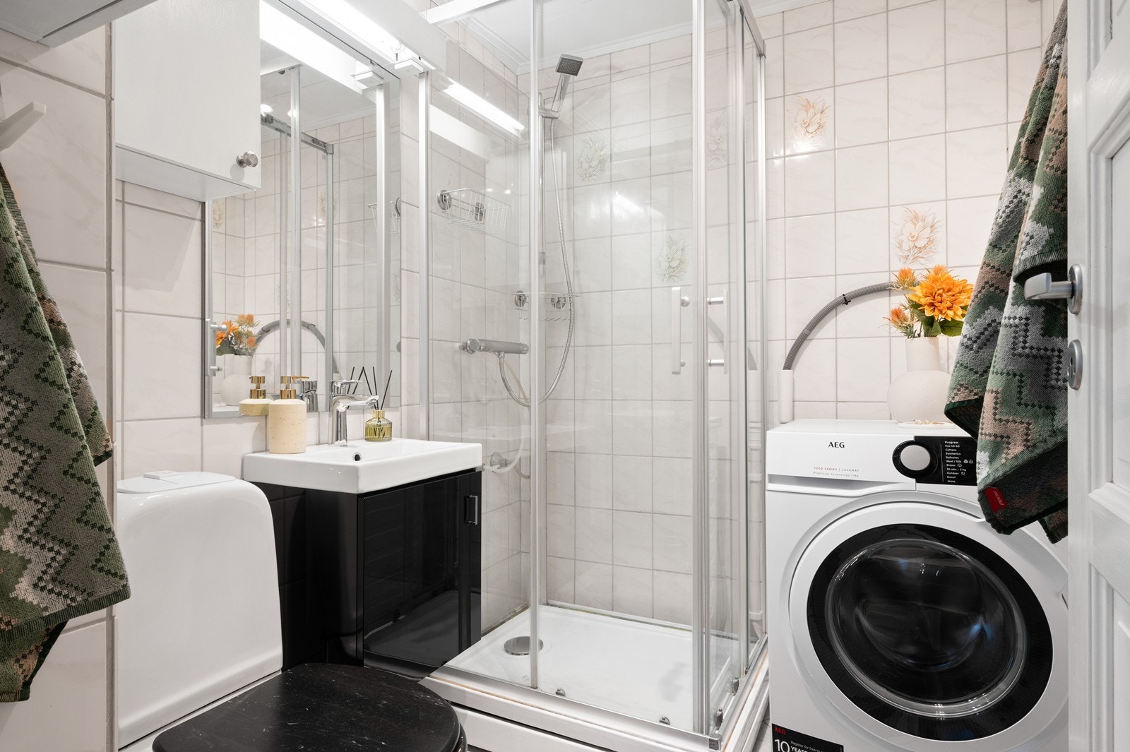 Flislagt bad med dusjkabinett, servant med underskap og toalett. Galleribilde