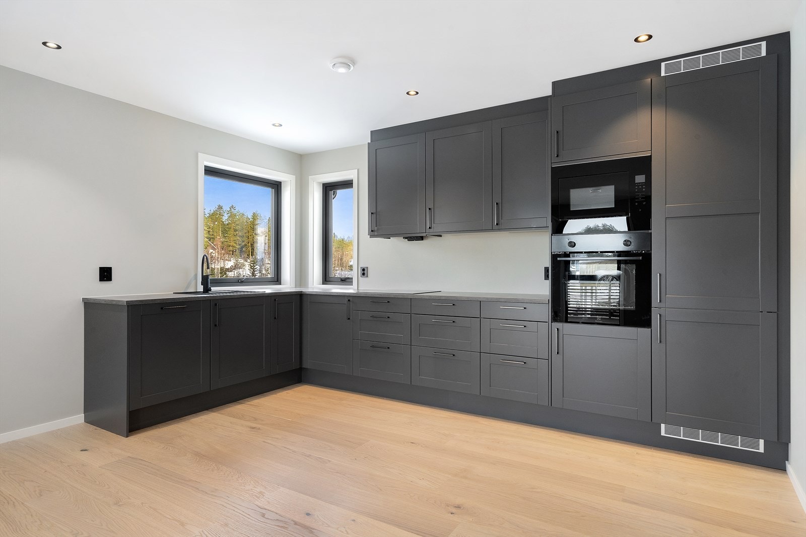 Delikat og moderne kjøkkeninnredning fra Sigdal med med grå, profilerte fronter og benkeplate av laminat. Galleribilde