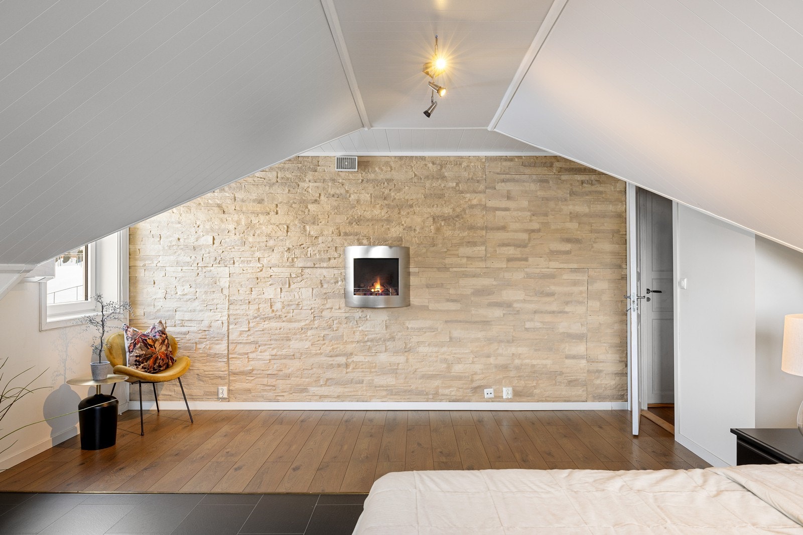 Hovedsoverommet har et lunt preg med innebygget gasspeis, fliser kombinert med den gjennomgående laminaten, og en flott fondvegg med dekorsten. Galleribilde