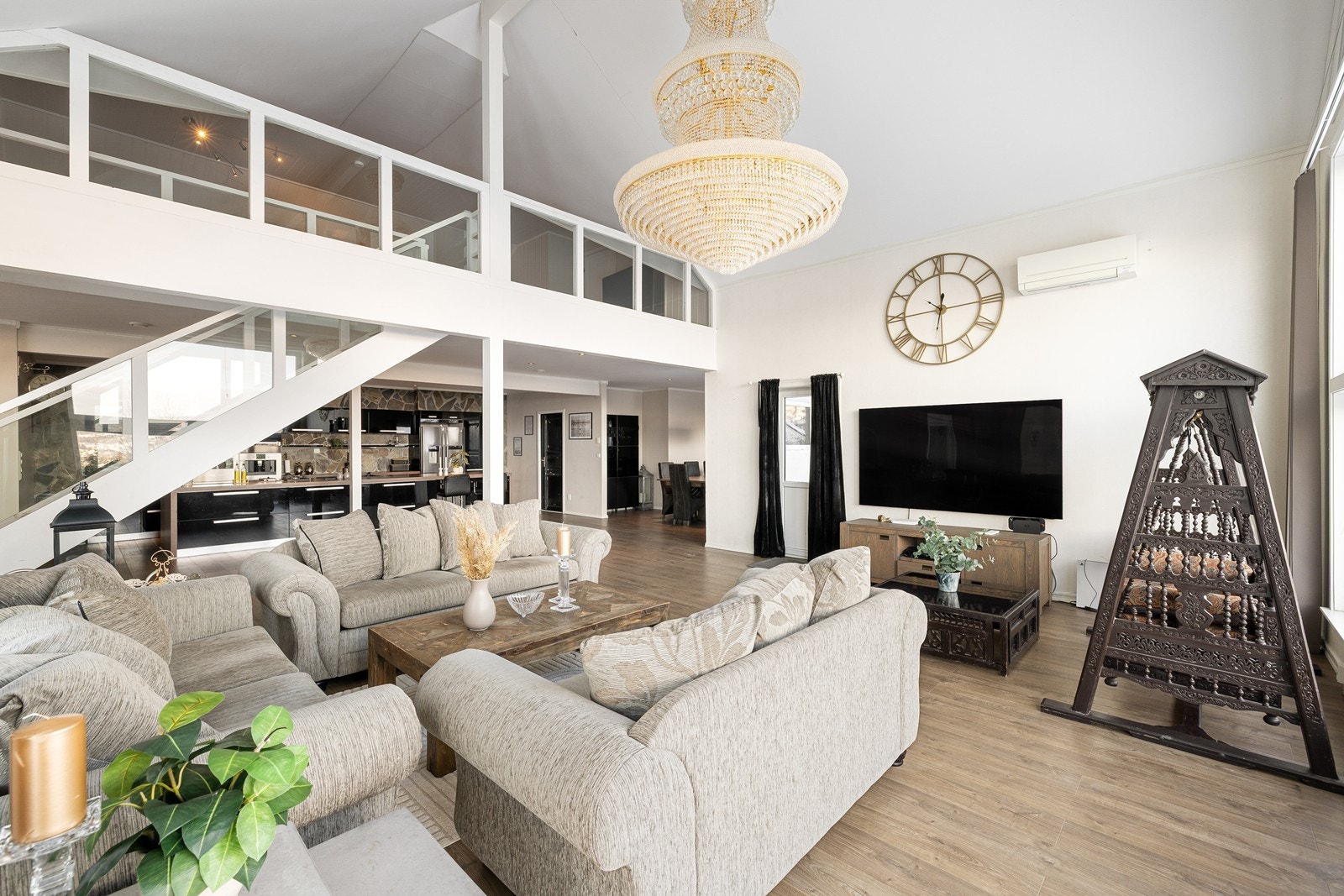 Boligens sosiale midtpunkt er utvilsomt den storslåtte stuen - Med en takhøyde på nærmere 7 meter og massive panoramavinduer som strekker seg over to etasjer, bades rommet i naturlig lys. Galleribilde