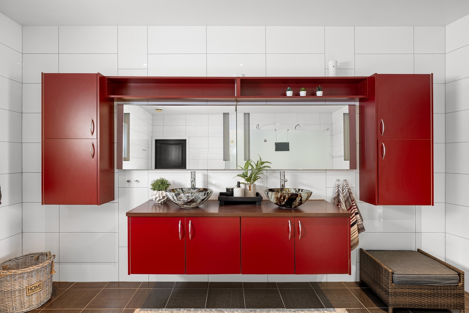 Badet er innredet med en dristig og stilig baderomsinnredning i rød høyglans, som skaper en spennende kontrast til de lyse veggflisene. Galleribilde