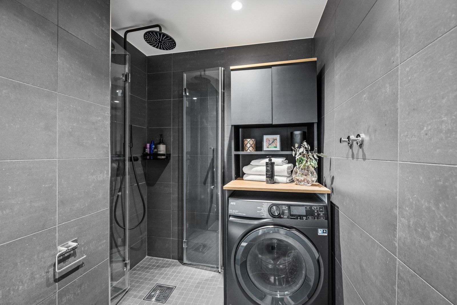Badet er videre utstyrt med vegghengt toalett, opplegg for vaskemaskin og dusjhjørne med regnfallsdusj og innfellbare glassdører. Galleribilde