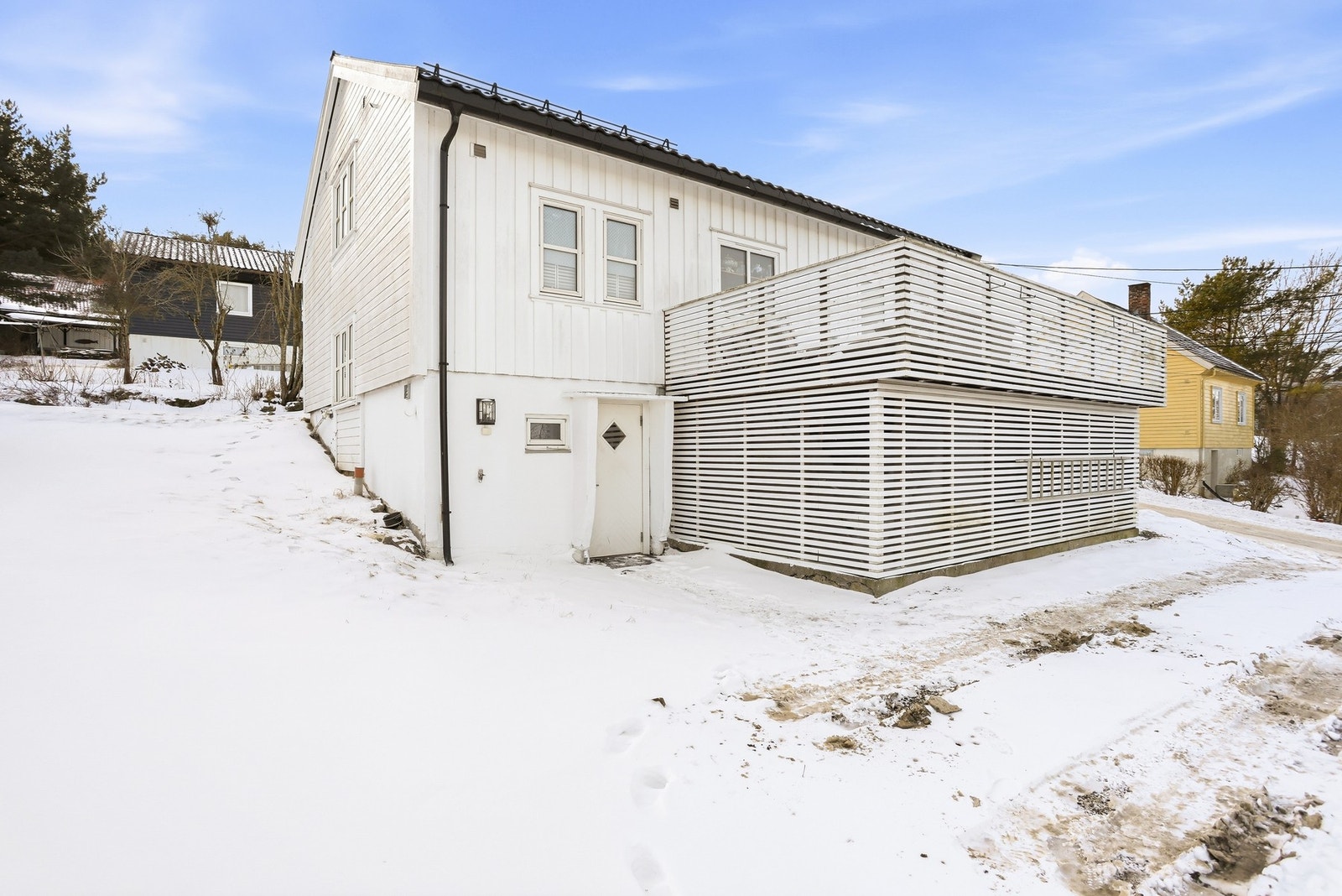 Bygget carport med balkong over med liggende spiler som vegger og rekkeverk. Galleribilde