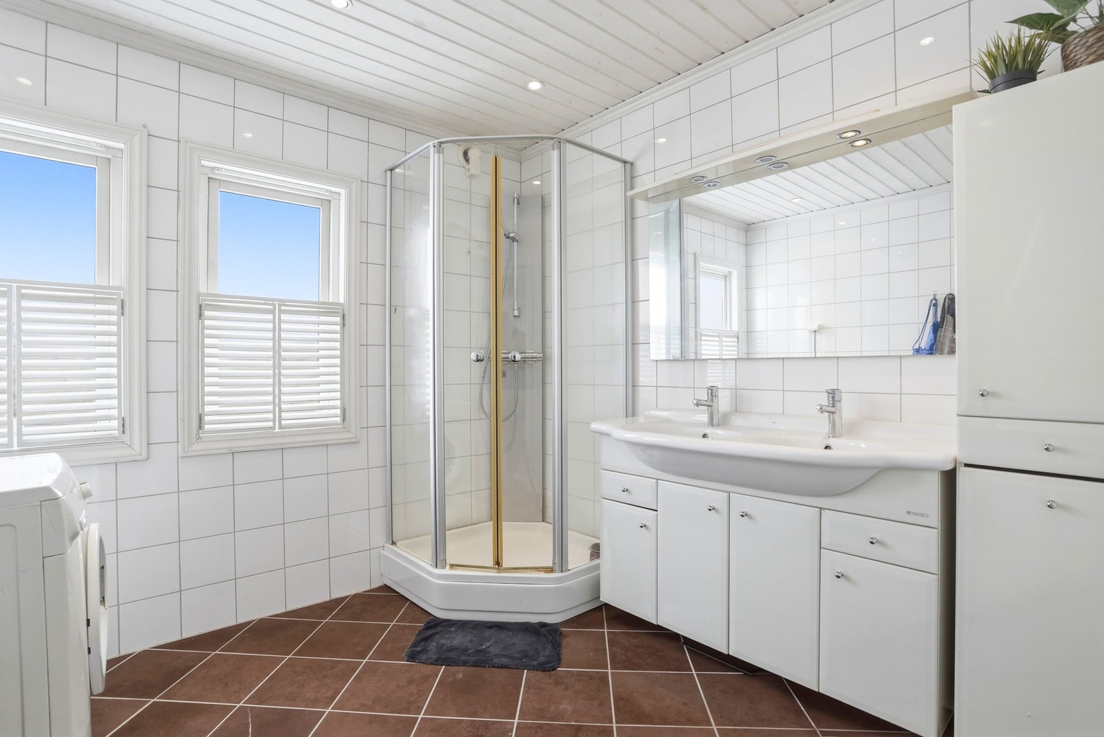 Pent flislagt hovedbad har dusjkabinett, vegghengt toalett og dobbel servantinnredning med hvite flate
fronter og speilskap. Galleribilde