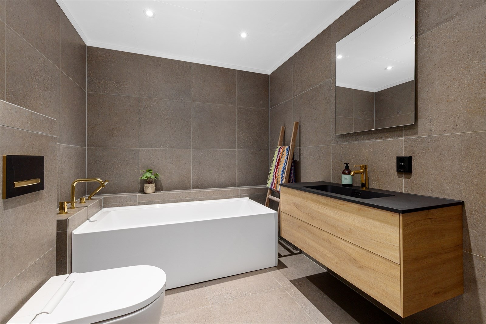 Nyere flislagt bad fra 2021 i 1.etg med servantinnredning, høyskap, badekar og Geberit spyletoalett. Galleribilde