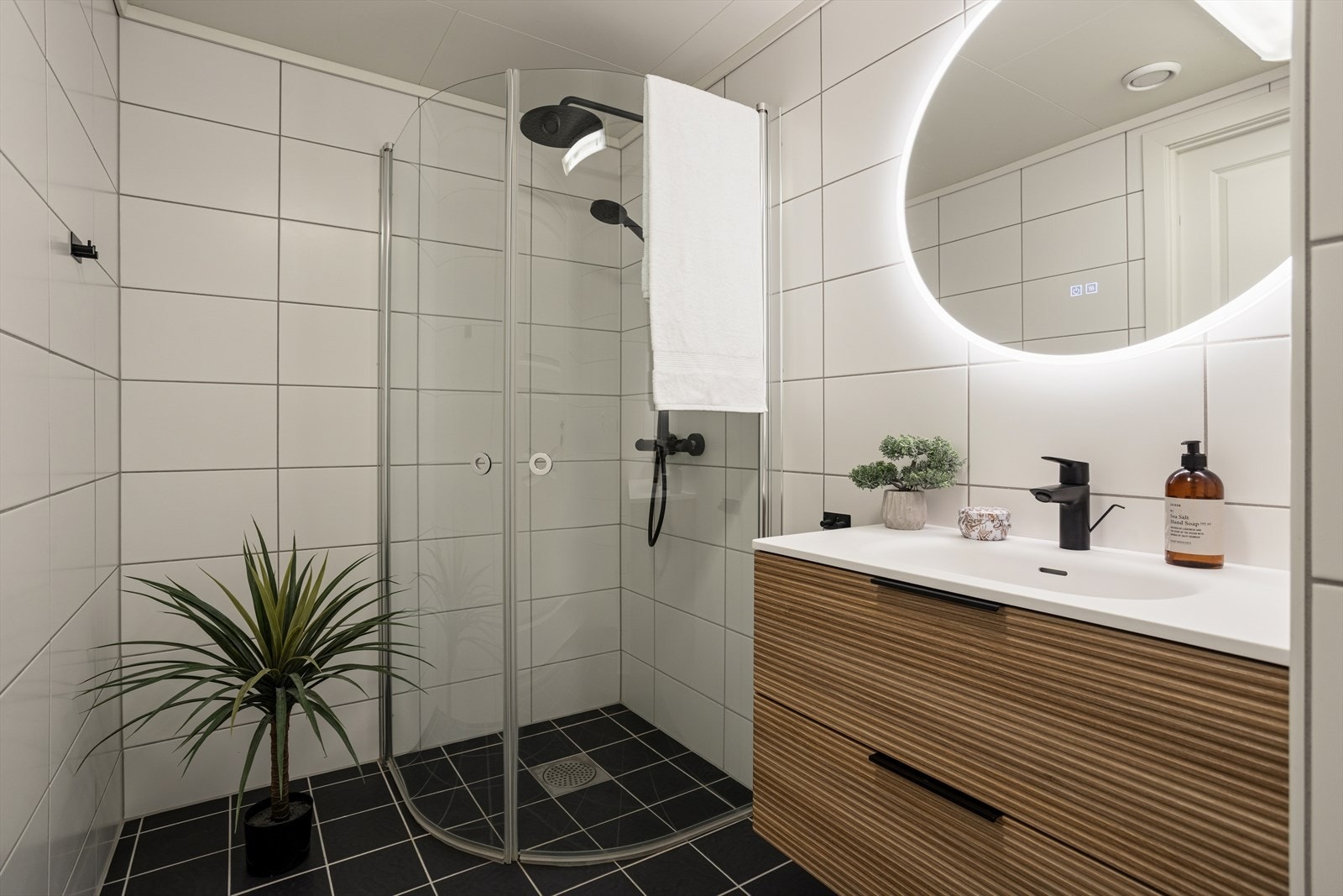 Pent oppusset bad med dusjhjørne i glass og praktiske løsninger. Galleribilde