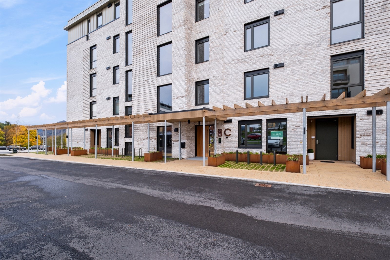 Inngangspartiet er beskyttet med en pergola, og det er blomsterkasser som gir et grønt inntrykk. Galleribilde