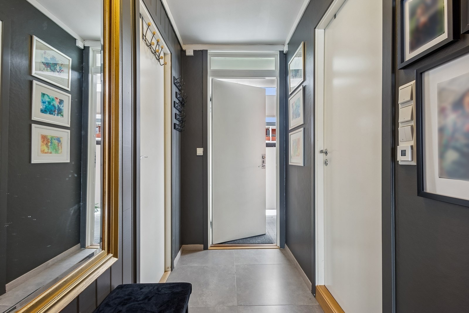 Gangen med flislagt gulv fungerer som et bindeledd mellom leilighetens ulike deler. Galleribilde