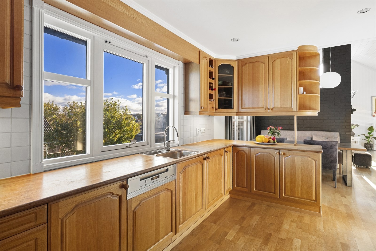 Åpent kjøkken som knytter stue og spisestue sammen for et sosialt hjem. Galleribilde