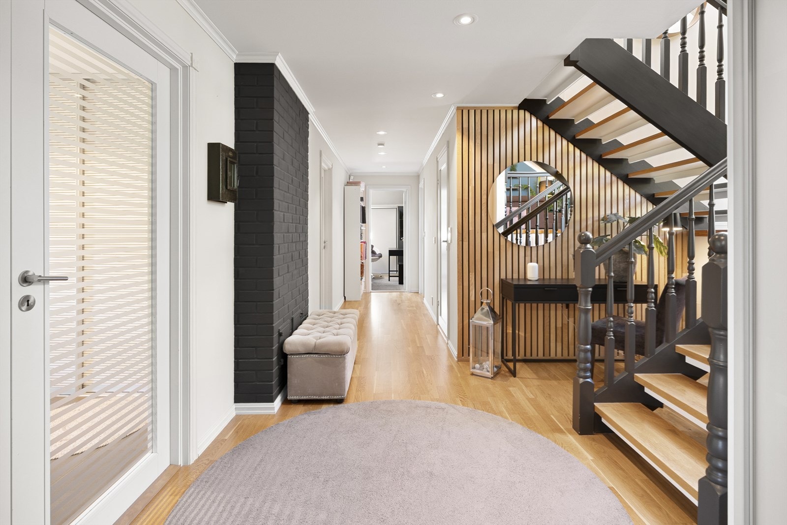 Naturlig lys strømmer gjennom gangen, som skaper en varm og innbydende forbindelse mellom soverommene og badene. Galleribilde