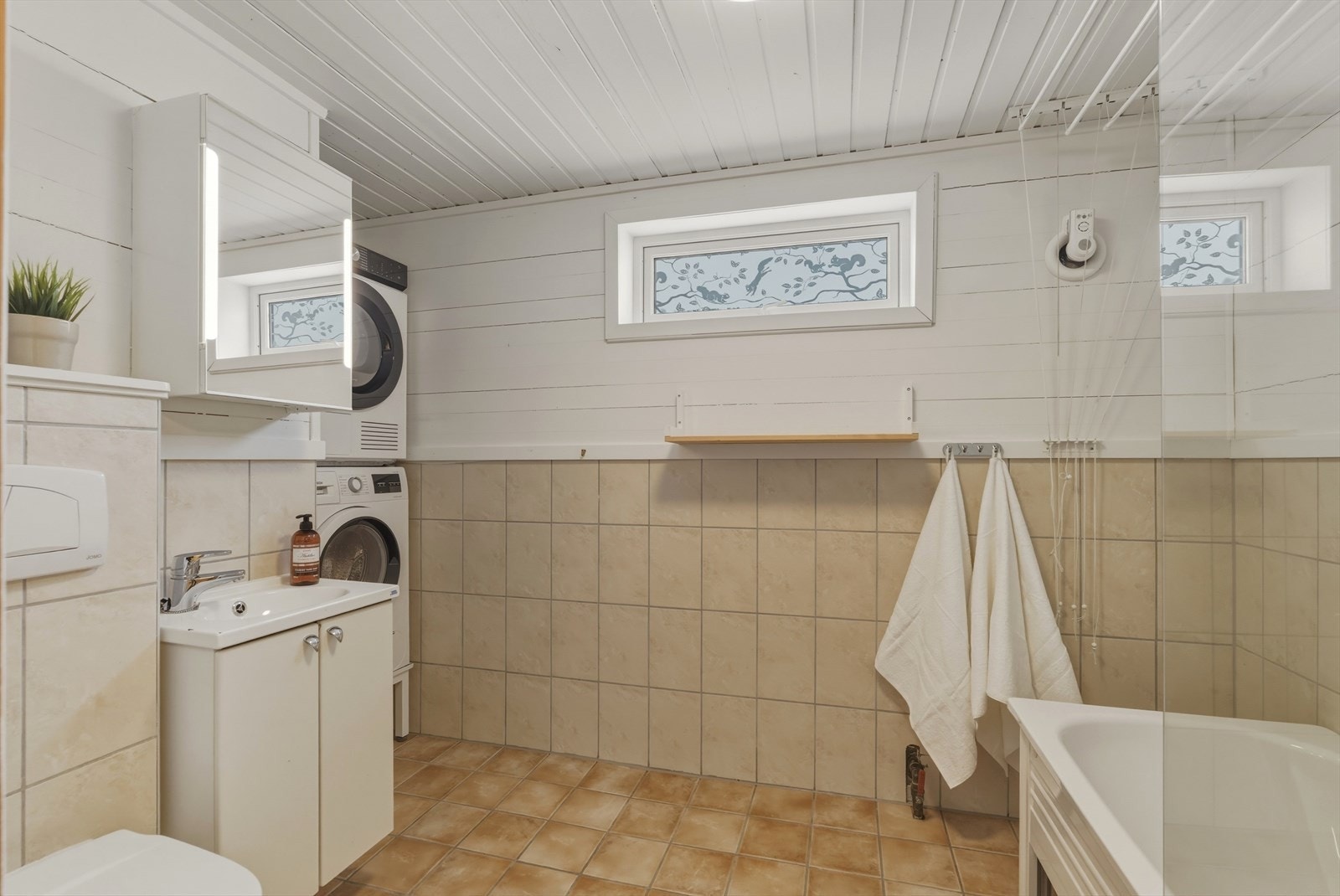 Baderommet har flislagt gulv med gulvvarme, og er utstyrt med toalett, badekar, moderne innredning og opplegg for vaskemaskin. Galleribilde