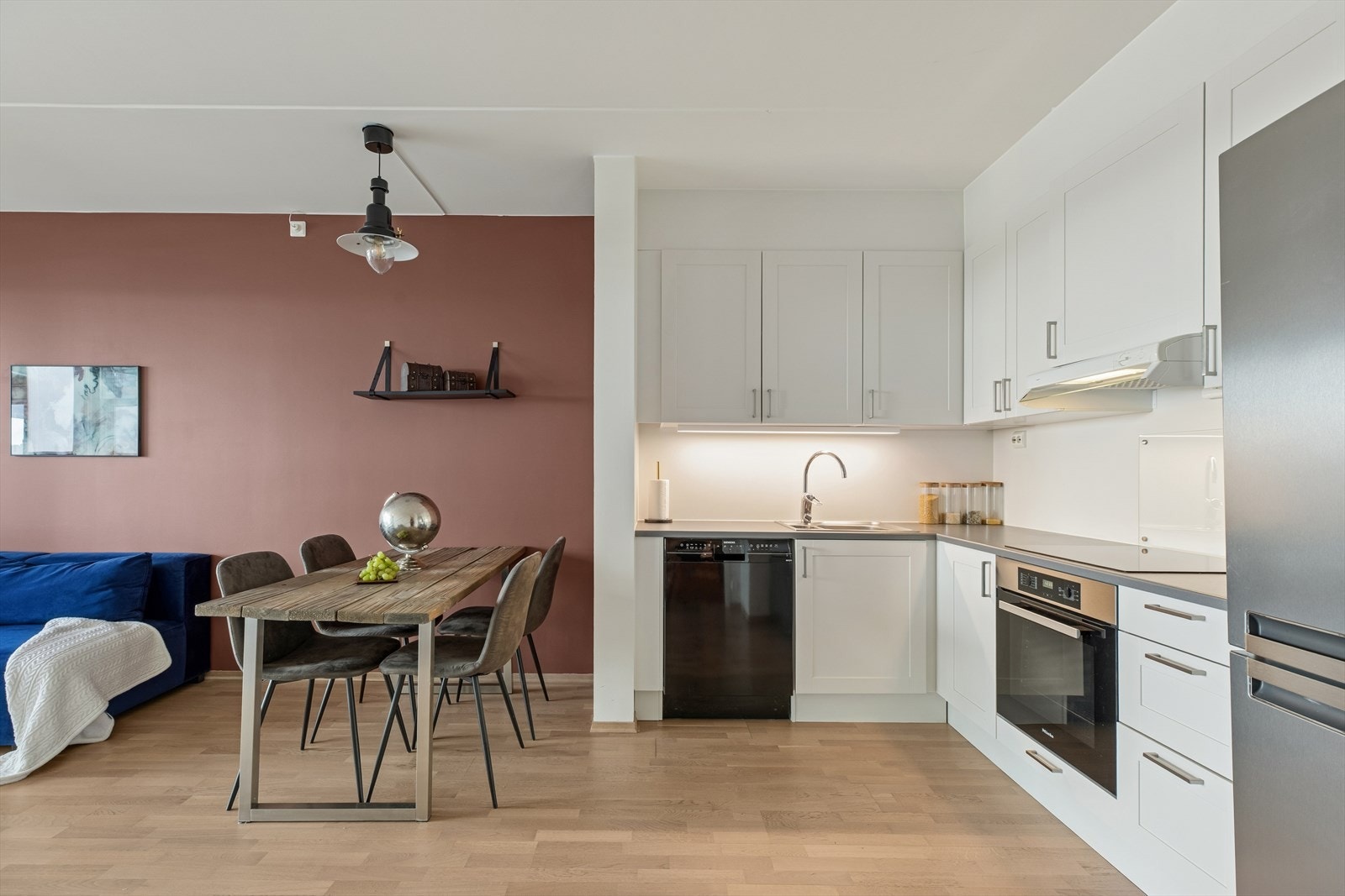 Kjøkkenet har en lys og tidløs innredning fra Sigdal, med profilerte, folierte fronter og en laminatbenkeplate med kjøkkenkran og nedfelt kum i rustfritt stål. Galleribilde