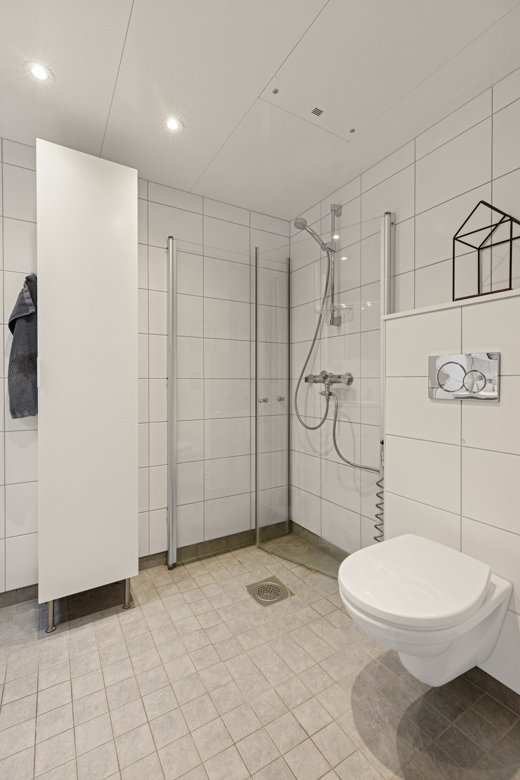 Badet er utstyrt med vegghengt toalett og dusjhjørne med glassdører. Galleribilde