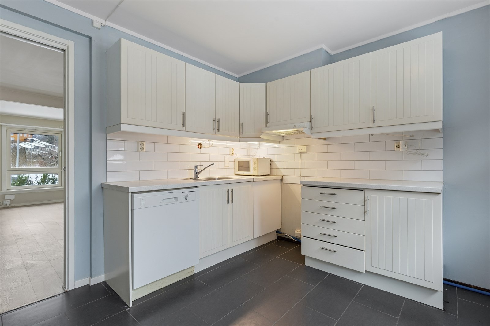 Kjøkken med profilerte, lakkerte fronter, laminert benkeplate og integrert oppvaskmaskin. Galleribilde