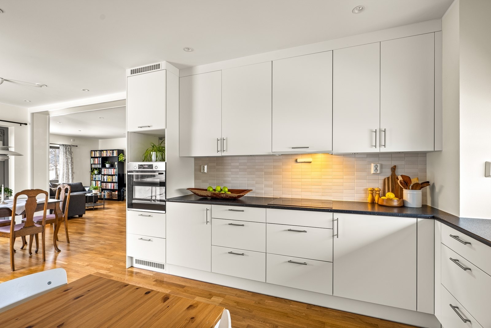 Kjøkkenet er innredet med glatte, lyse fronter og en slitesterk benkeplate i mørk laminat. Galleribilde