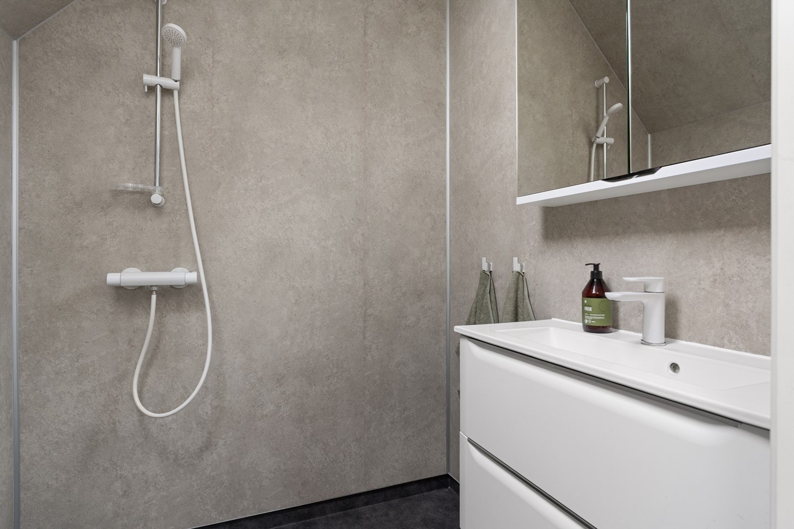 Badet er innredet med vegghengt toalett, dusjhjørne og innredning med servant. Galleribilde