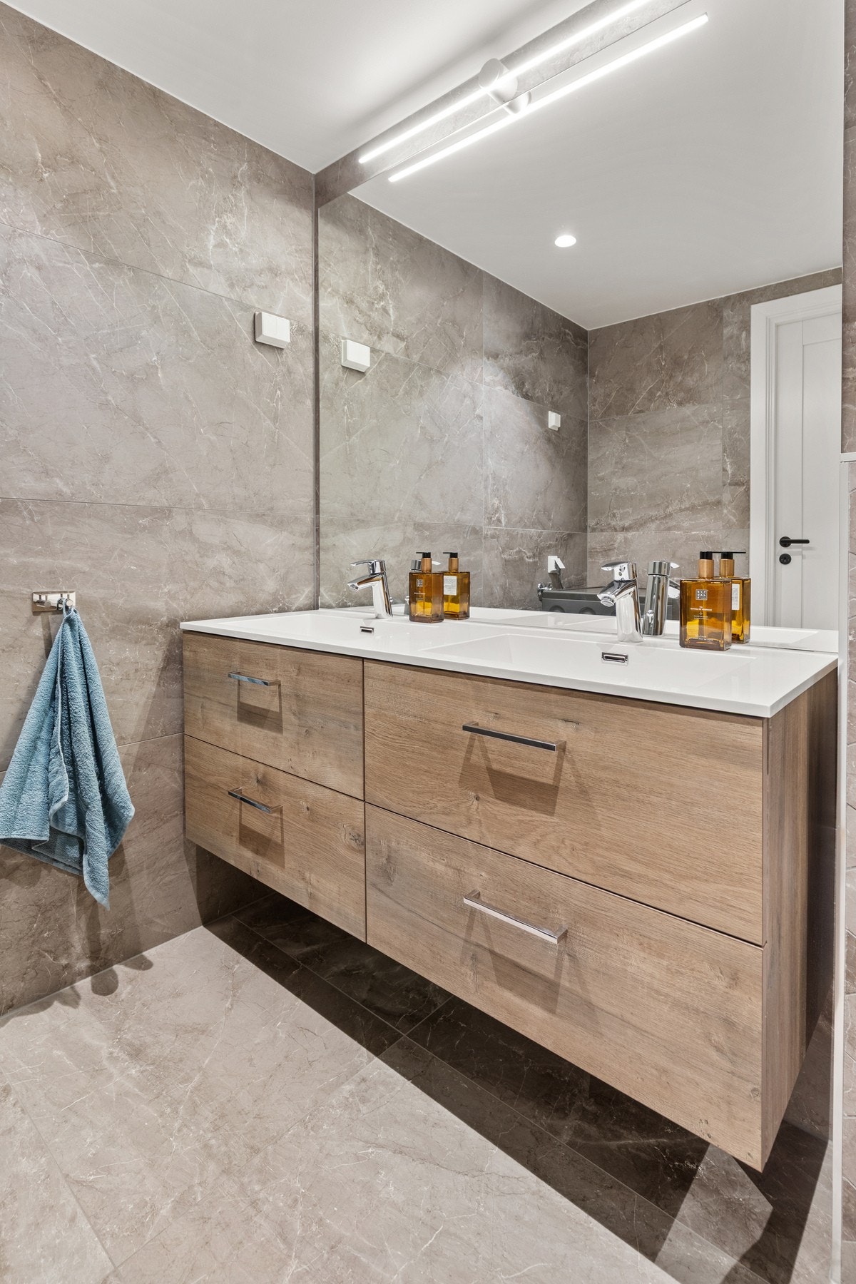 Rommet er helfliset og innredet med vegghengt toalett, servantinnredning speil med belysning og dusjhjørne med glassvegger. Galleribilde