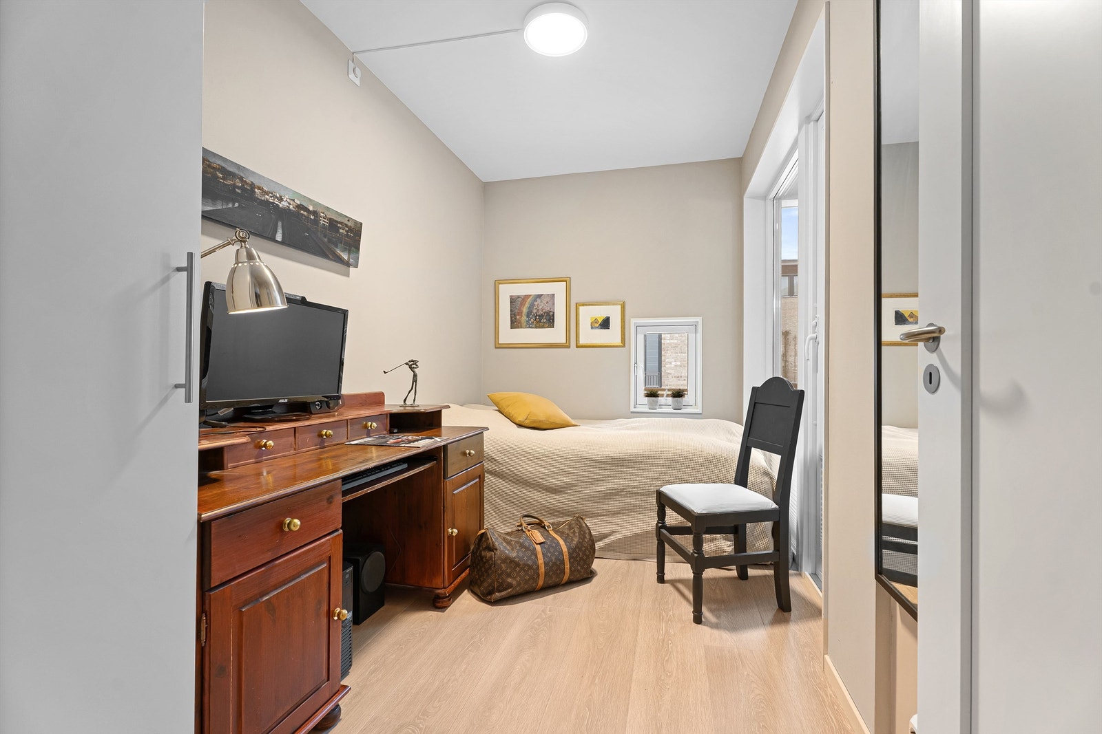 Soverom 1 - Praktisk soverom med både plass til garderobe, skrivepult og dobbeltseng med tilgang til balkong og et lite vindu Galleribilde