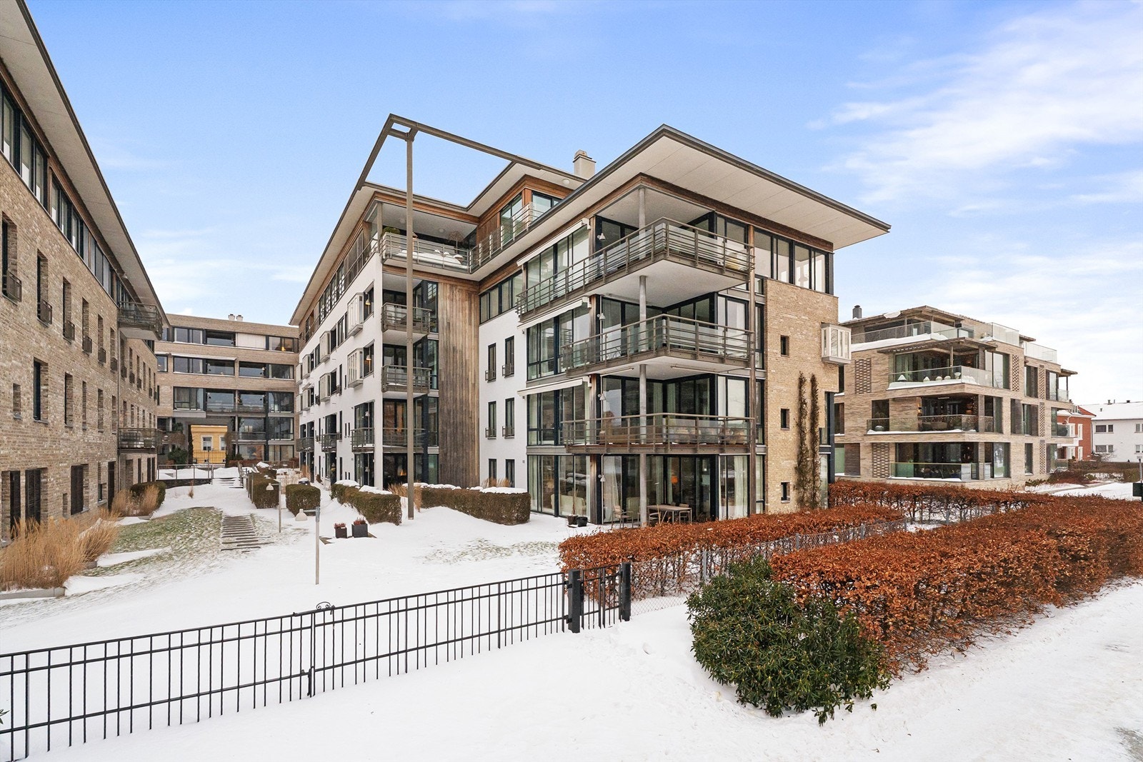 Fasaden sett fra Strandpromenaden, leiligheten ligger neste innerst på høyre side hvor uteplassen åpner seg opp med hyggelige fellesarealer Galleribilde