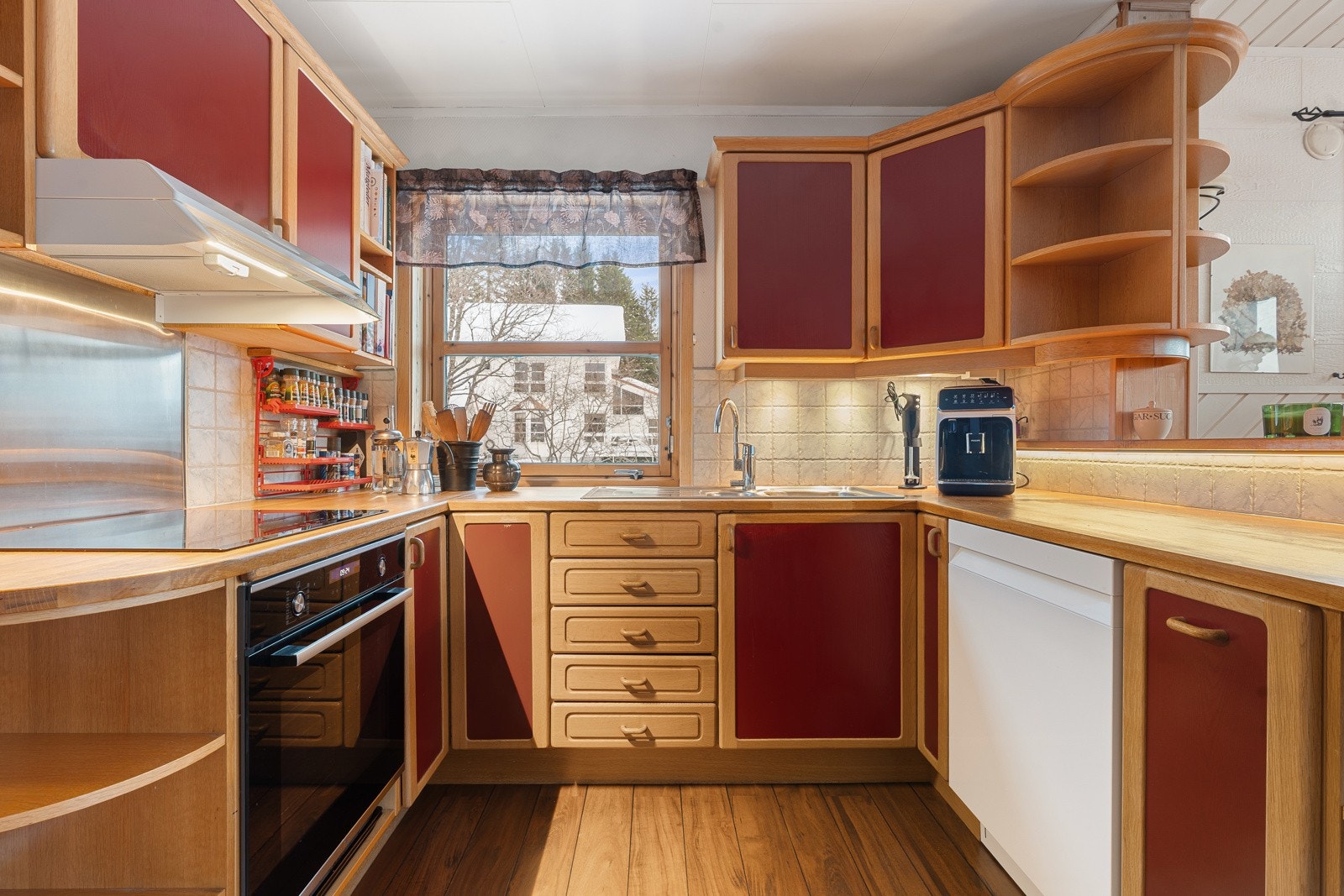 Kjøkken med heltre fronter, integrert stekeovn og induksjonstopp, med vindu over benken Galleribilde