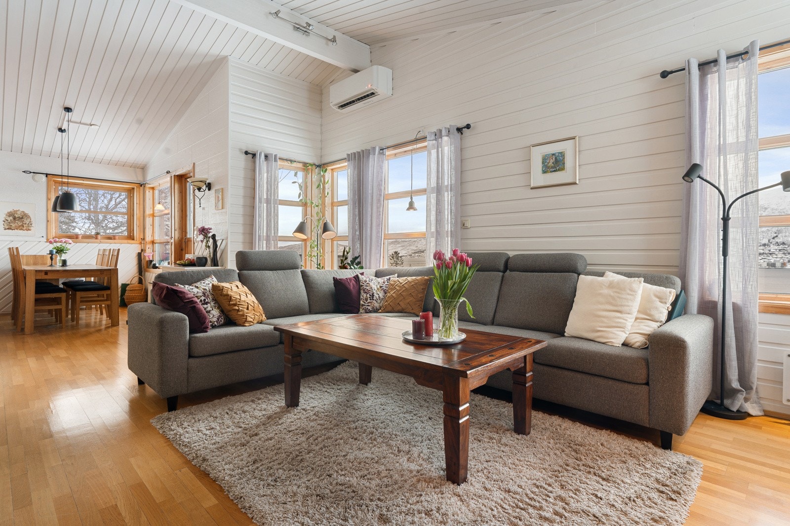 Lys og romslig stue med høy takhøyde og vinduer i tre himmelretninger - gir rikelig med naturlig lys inn Galleribilde