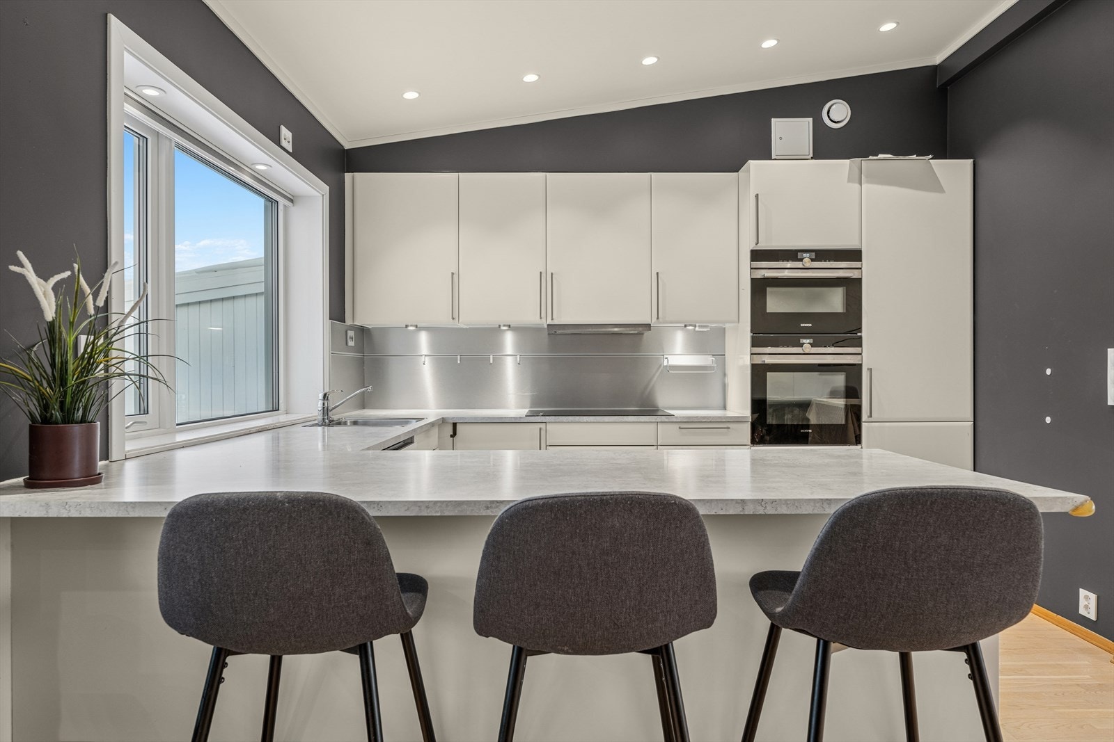 Lyst og tidløst kjøkken med praktisk bar-løsning mot stue. Galleribilde