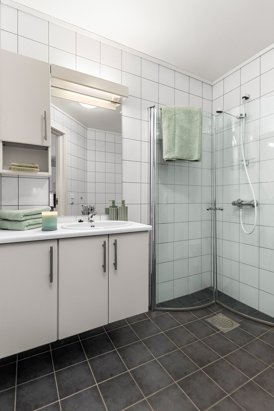 Badet er innredet med servantskap, innfellbare dusjdører og vegghengt toalett. Galleribilde