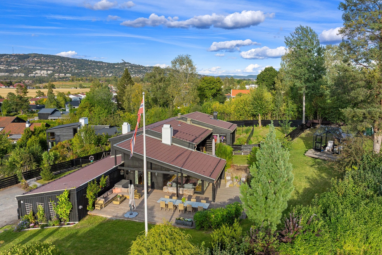 Pent opparbeidet tom med solrike uteplasser, flaggstang og drivhus Galleribilde