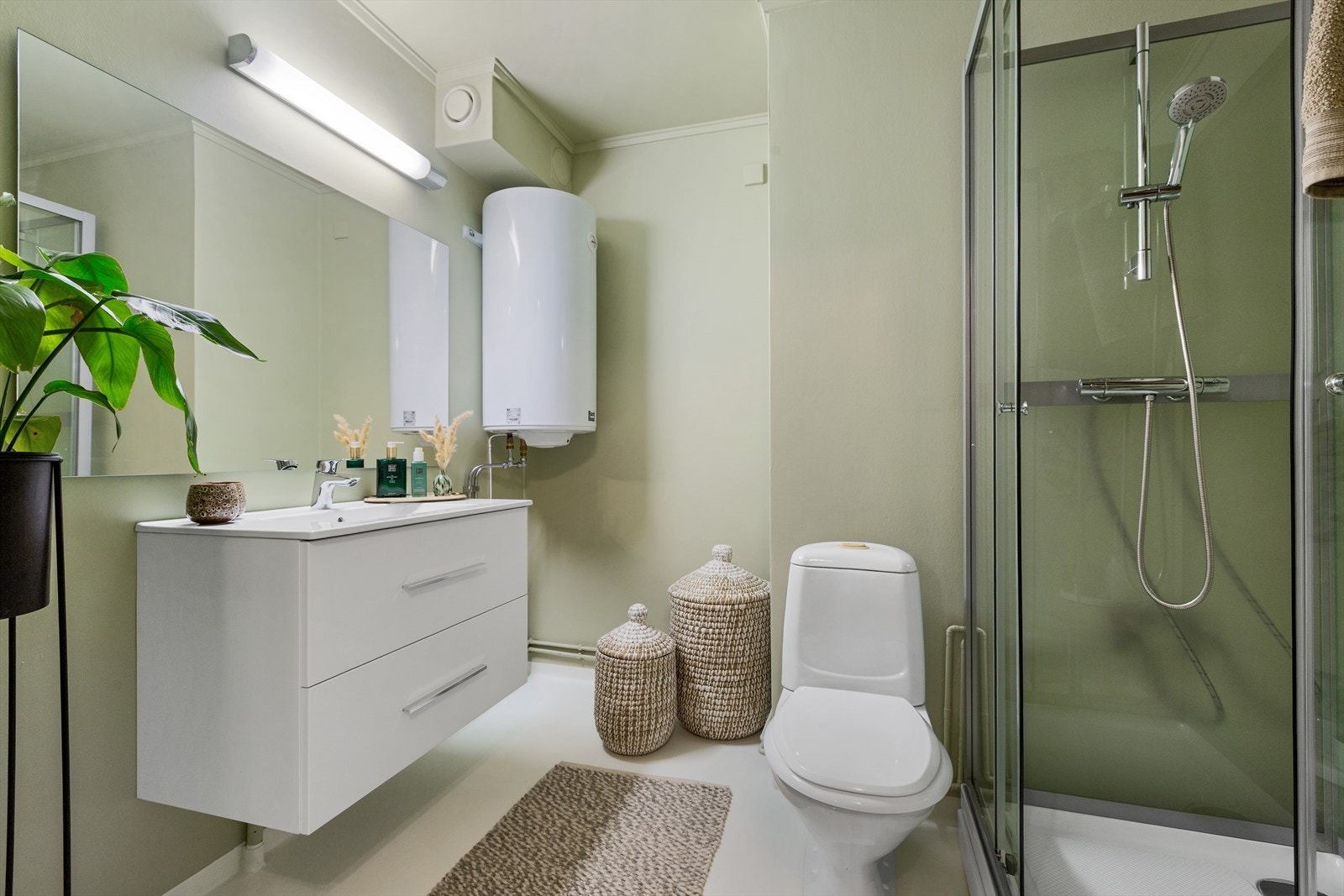 Badet har toalett, dusjkabinett, innredning med servant, speil med overlys og ny varmtvannstank. Galleribilde