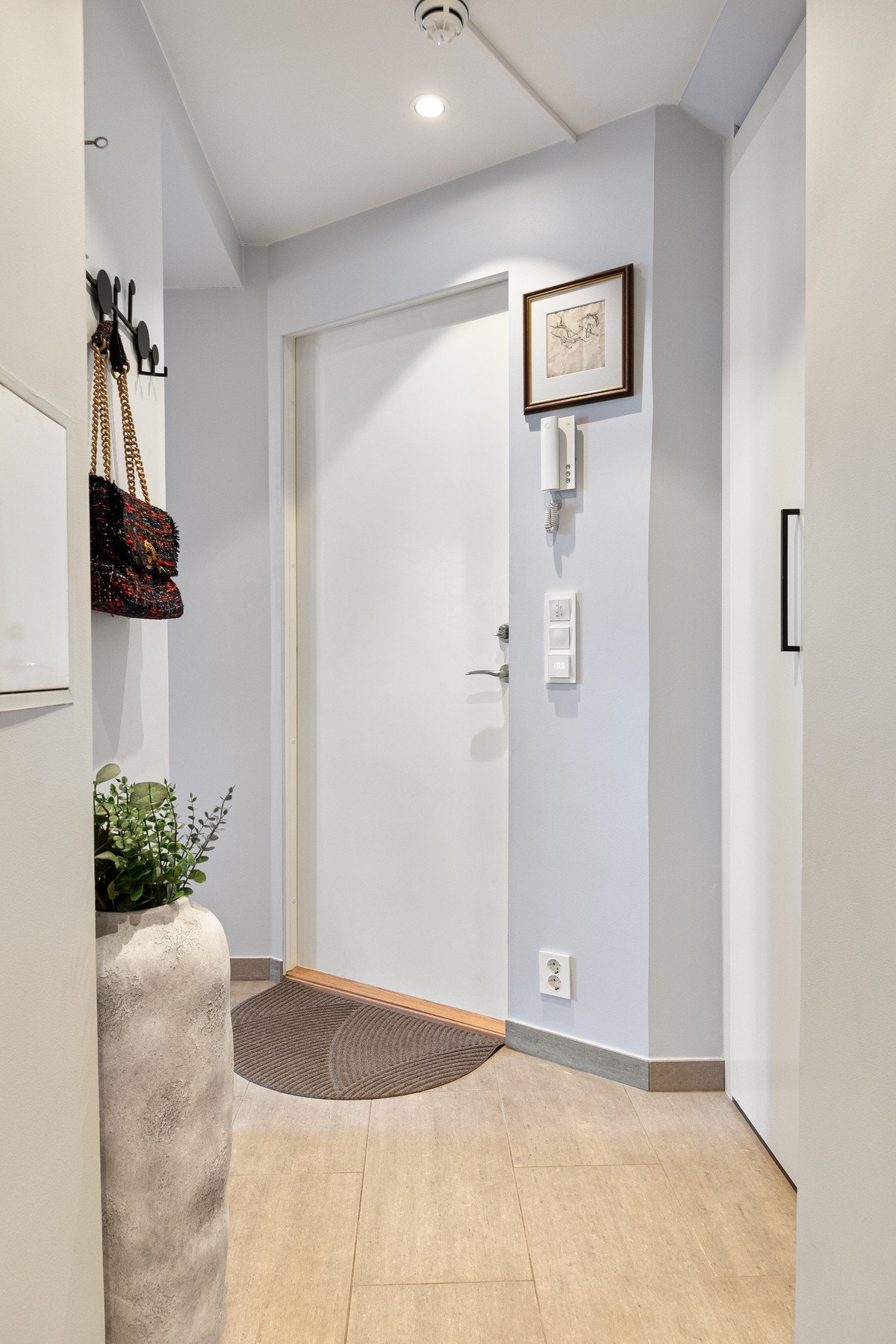 Entréen har flislagt gulv som er både praktisk og slitesterkt, kombinert med lyse, nøytrale veggflater som bidrar til en luftig romfølelse. Galleribilde
