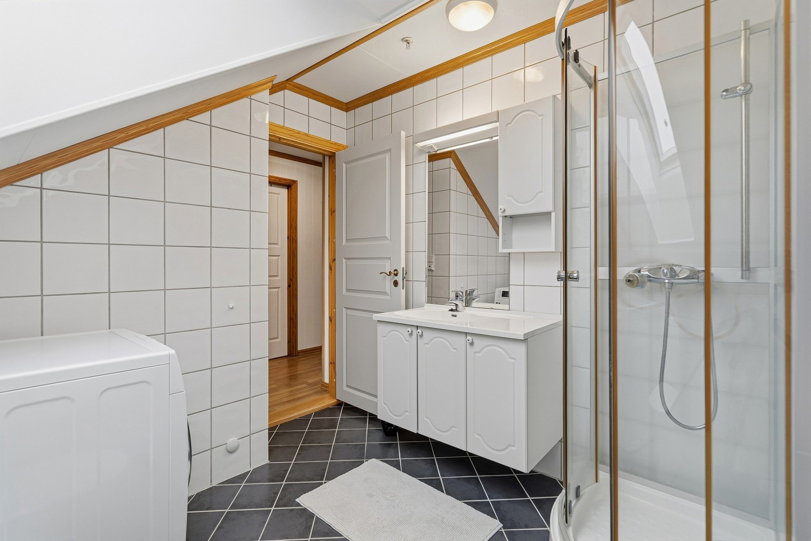 Badet er flislagt med varmekabler, dusjkabinett, servant, toalett og opplegg for vaskemaskin. Galleribilde