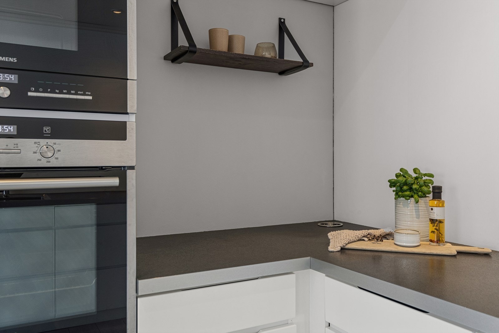 Kjøkken med gjennomtenkte detaljer. Komfyr i arbeidshøyde og stikkontakt integrert i benkeplaten. Galleribilde