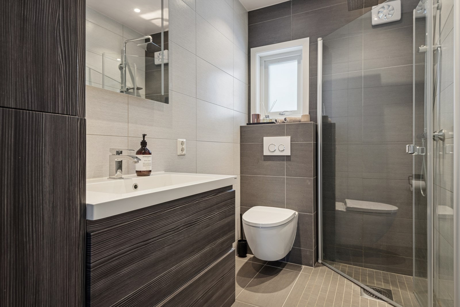 Lekkert bad fra 2015 med fliser, dusj med glassvegger og vegghengt toalett. Galleribilde