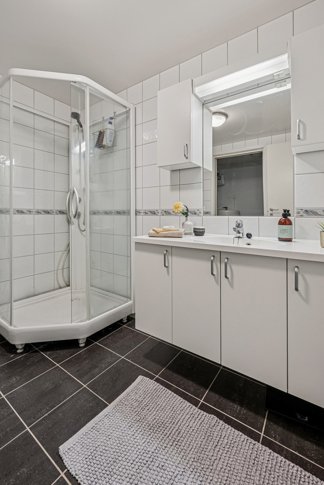 Badet er ellers utstyrt med dusjkabinett, vegghengt toalett og baderomsinnredning med god lagringsplass og nedfelt servant. Galleribilde