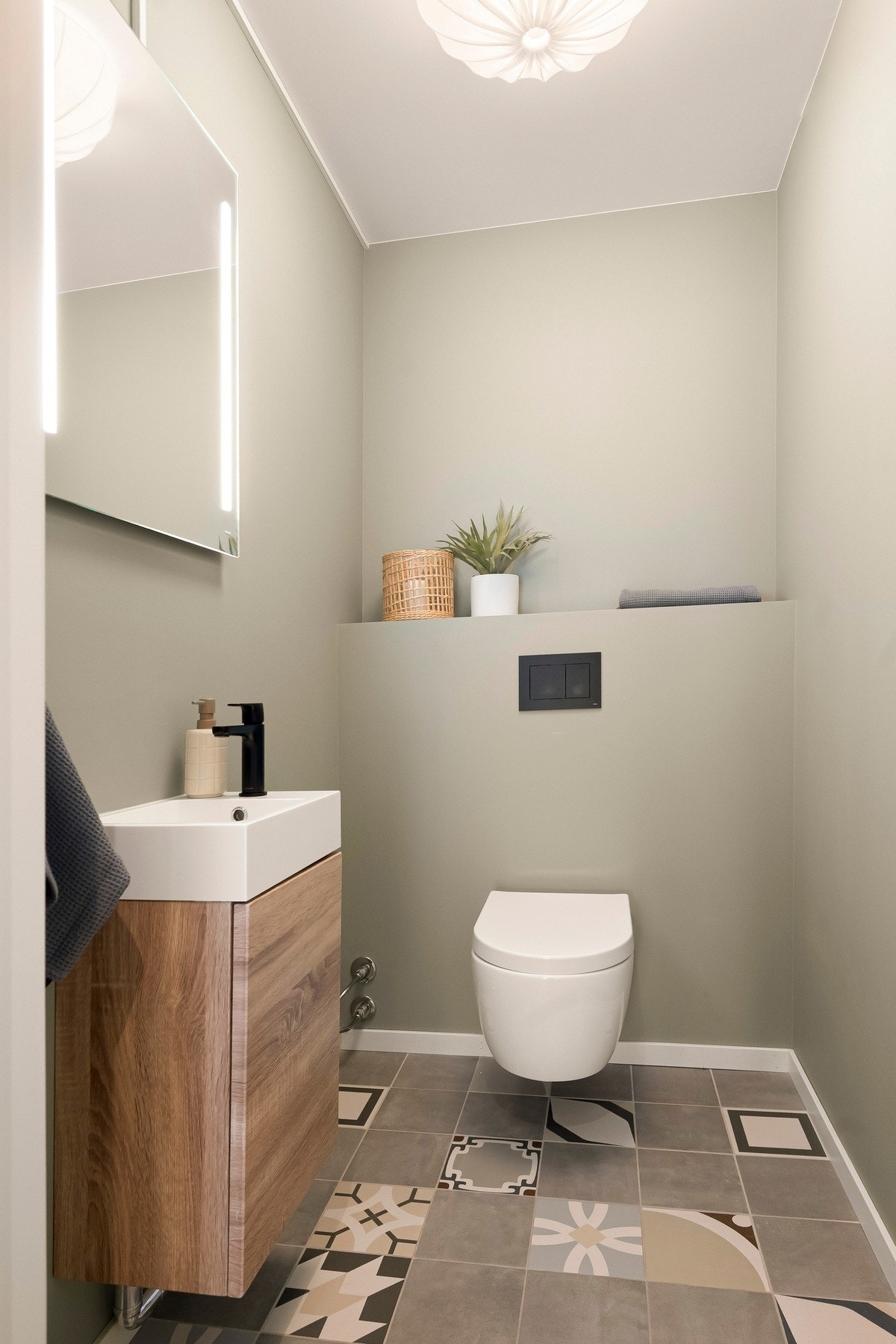 Toalettrommet inneholder vegghengt toalett, servantseksjon med skap og speil med integrert lys. Galleribilde