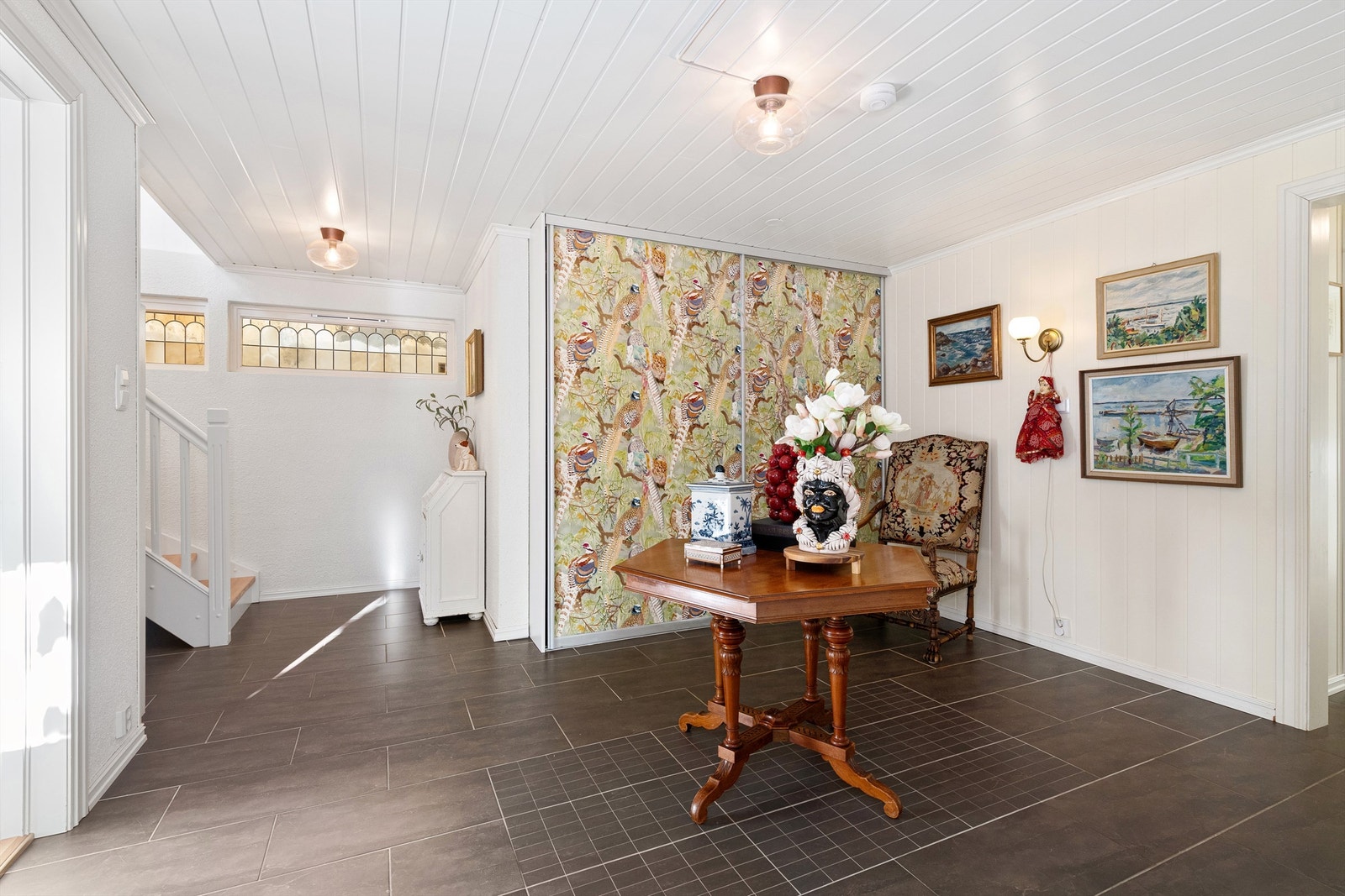 Romslig hall/trapperom i underetasjen med skyvedørsgarderobe Galleribilde