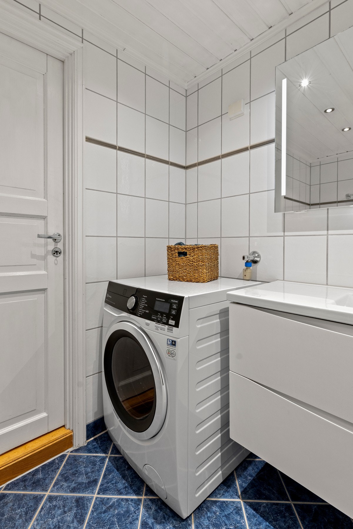 Badet er utstyrt med servant, veggfestet klosett, badekar og opplegg til vaskemaskin Galleribilde