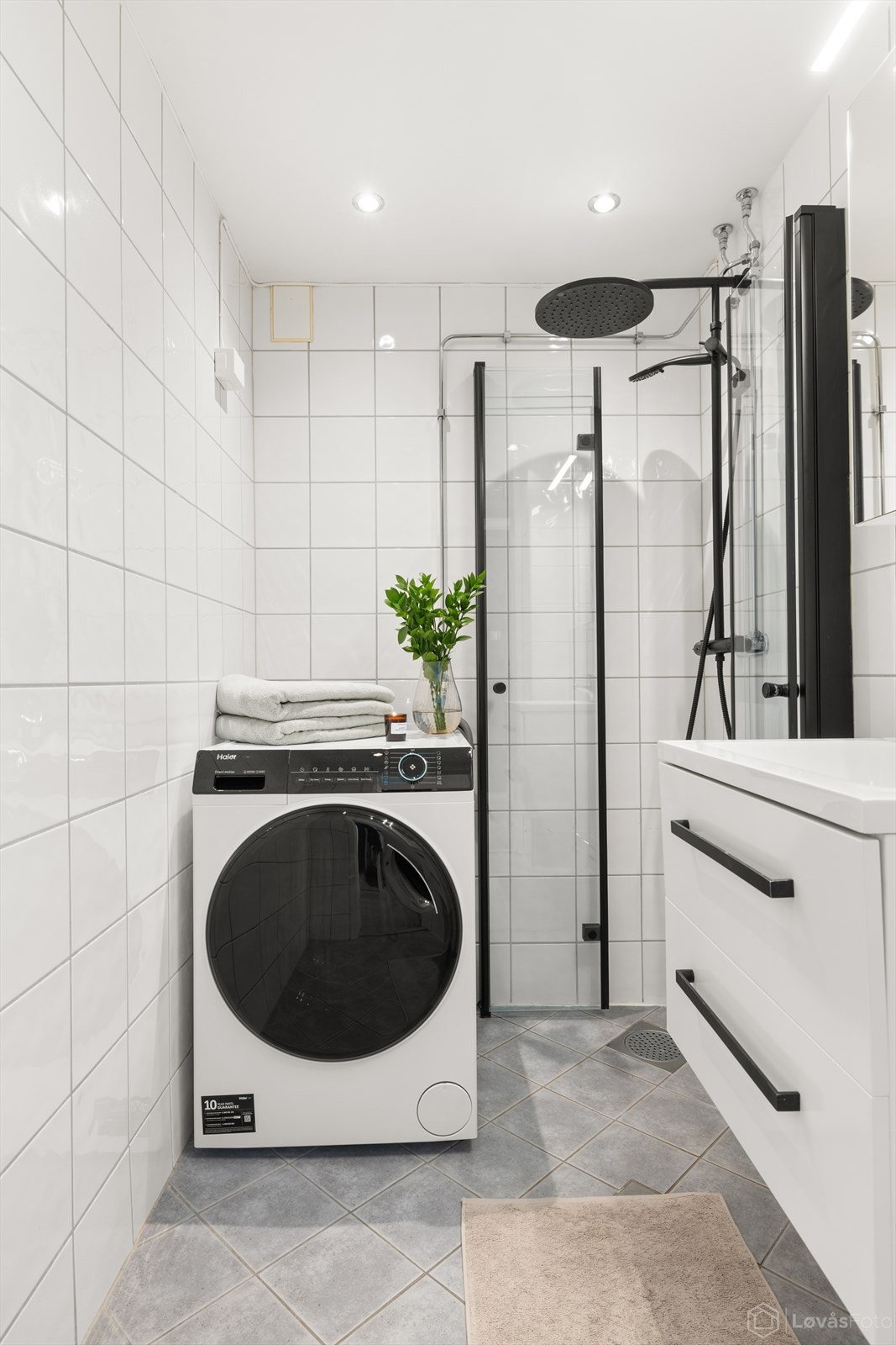 Baderommet | Flott bad med flislagte vegger, gulv med varmekabler og stilrene, svarte detaljer. Badet er innredet med servant med innredning, dusjhjørne med regnfallsdusj og opplegg for vaskemaskin. Galleribilde